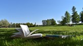 Foto på en uppslagen bok som ligger på en gräsmatta.