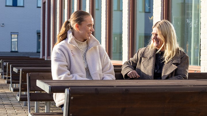 Ebba Löfgren, vice ordförande med utbildningspolitiskt ansvar vid Örebro studentkår och Karin Blomberg, dekan vid Fakulteten för medicin och hälsa sitter på en bänk utomhus.