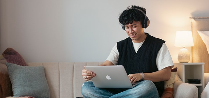 En student sitter i soffan med sin laptop.