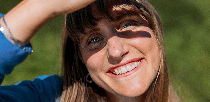 Nyfiken och glad kvinna kollar in i kameran.