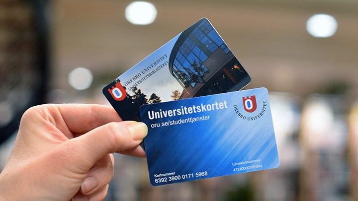 Foto på en hand som håller i ett lånekort och ett universitetskort.