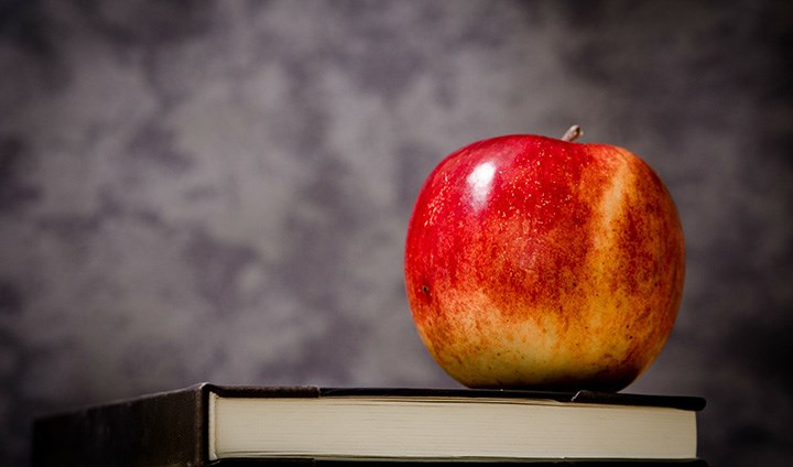 Äpple som ligger ovanpå böcker