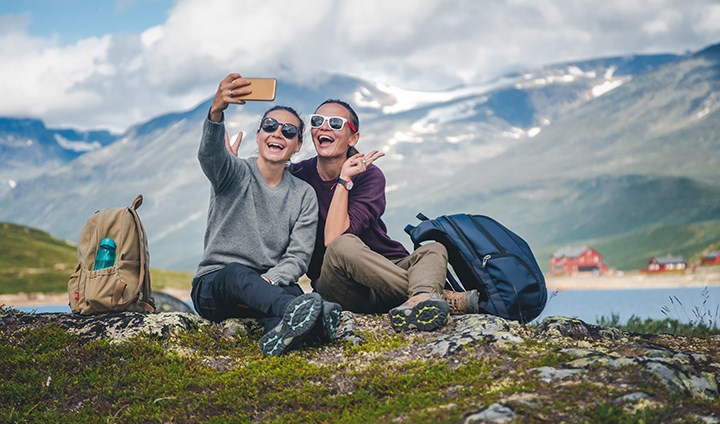 Två studenter tar en selfie i naturen med vacker bergsbakgrund