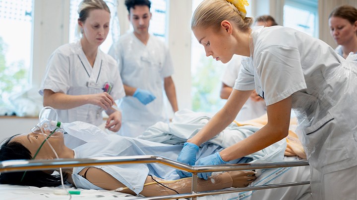 En grupp studenter arbetar tillsammans med en mänsklig docka. De ger dockan omvårdnad.