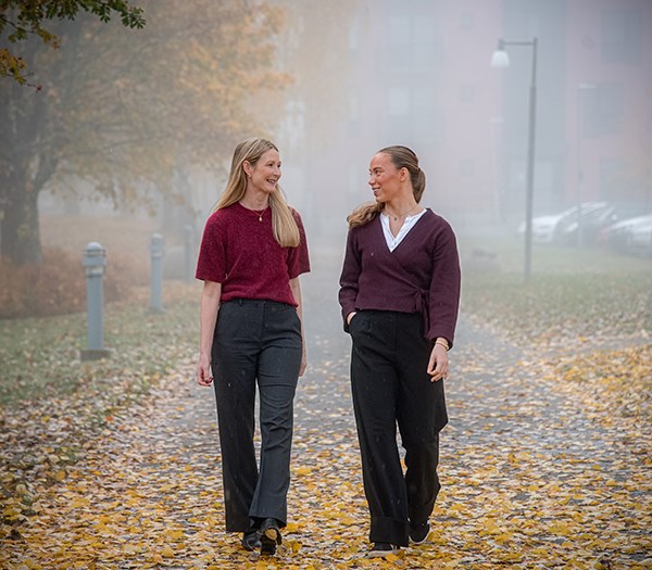 Elin Vimefall och Ebba Löfgren går på en gata. Det är höst med gula löv på gatan och dimma.