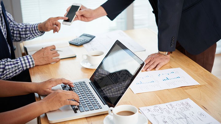 An office table with hands and computers