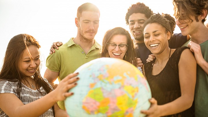  A group of people is holding a globe. They are laughing.