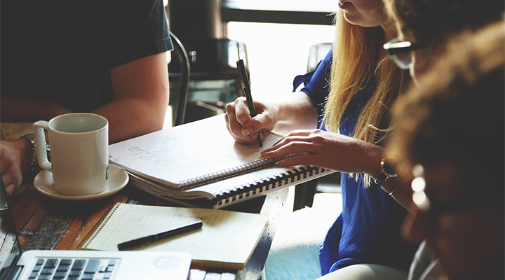 Some people sit around a table and write.