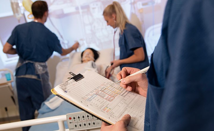 sjukskötsköterskestudenter arbetar tillsammans med en docka i mänsklig storlek som de vårdar.  