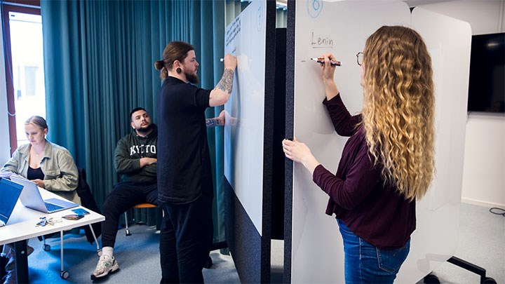 Studenter skriver på whiteboards på hjul.