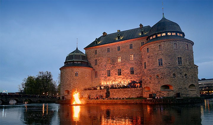 Örebro slott med valborgsbrasan i Svartån och kören framför slottet.