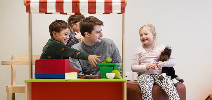 En pedagog tillsammans med tre barn leker kiosk.