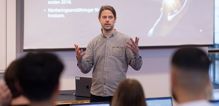 En lärare föreläser för ett gäng studenter i en föreläsningssal.