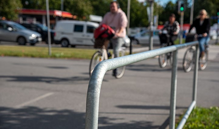 Ett räcke vid en cykelbana. I bakgrunden syns suddiga cyklister.