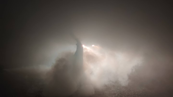 Smoky environment with the silhouette of a person and headlights