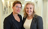 Åsa Källström och Susanne Srand står bredvid varandra i en ljus korridor.