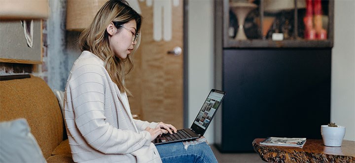 Kvinna sitter i en soffa med en laptop i knäet