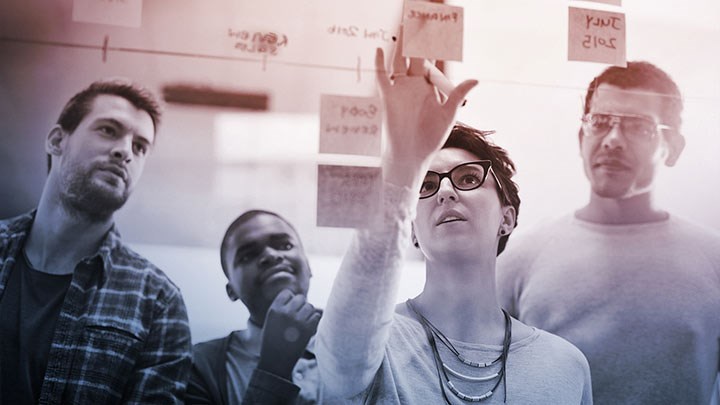 Människor som tittar på en skärm vända mot oss.