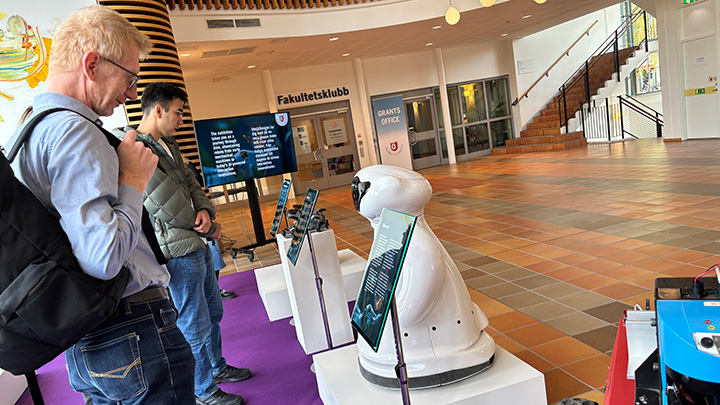 Two people looking at a white AI robot.