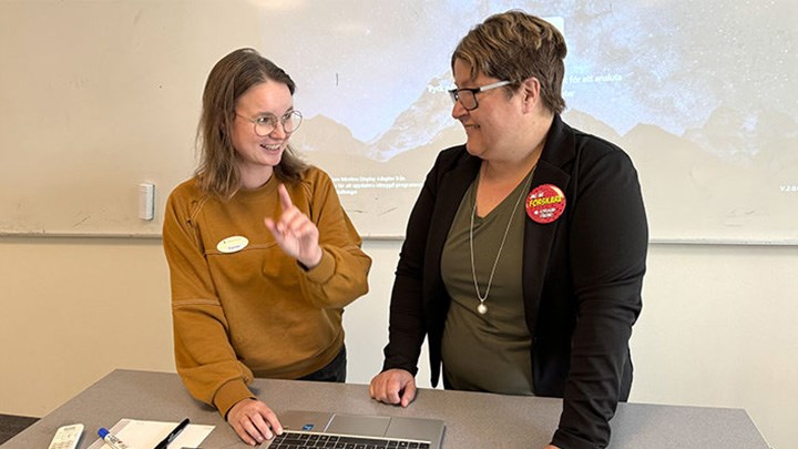 Karin Franzén och Kerstin Imrell står vid ett skrivbord. Bakom dem syns en whiteboard. 