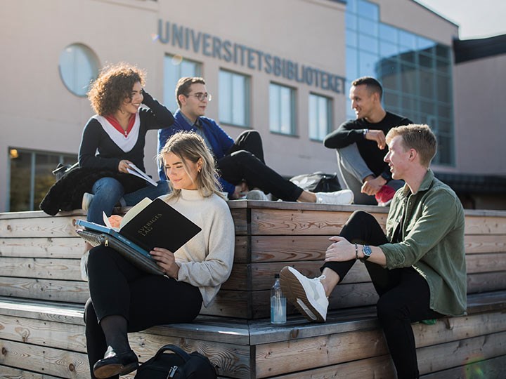 Fem studentambassadörer sitter utanför biblioteket.