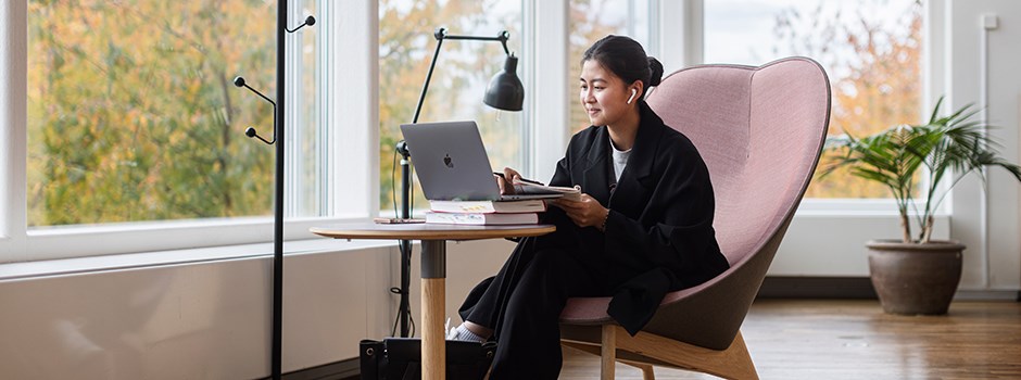 En kvinnlig student sitter vid en dator och pluggar.