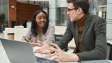 Two people are conversing by a computer