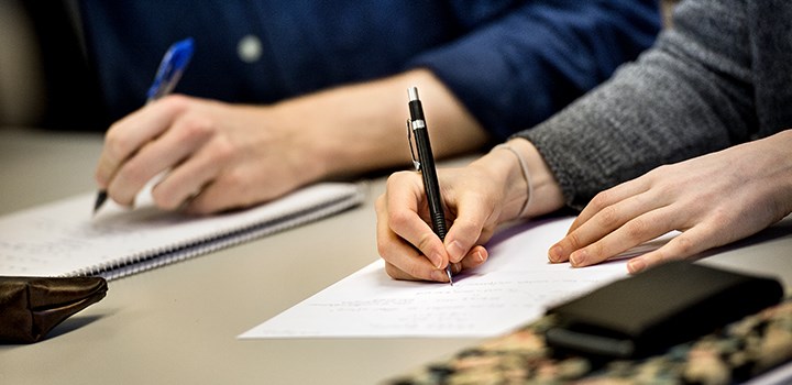 Photo of a hand writing on a paper.