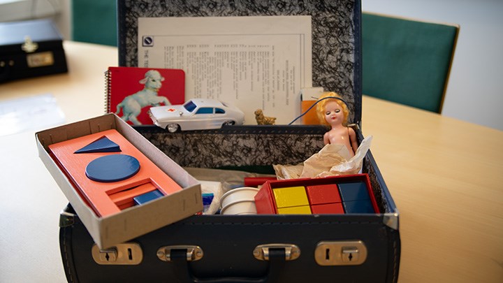 En portfölj med ett äldre test som användes för att bedöma utvecklingen hos små barn. I portföljen finns bland annat klossar, en bok, en bil och en docka.