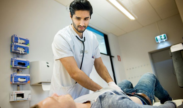 En läkarstudent undersöker en patient.