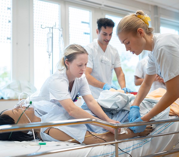 Sjuksköterskestudenter arbetar med en docka i mänsklig storlek.