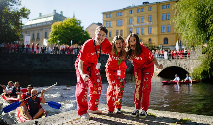 Glada studenter vid svartån i Örebro med andra studenter som paddlar i bakgrunden.