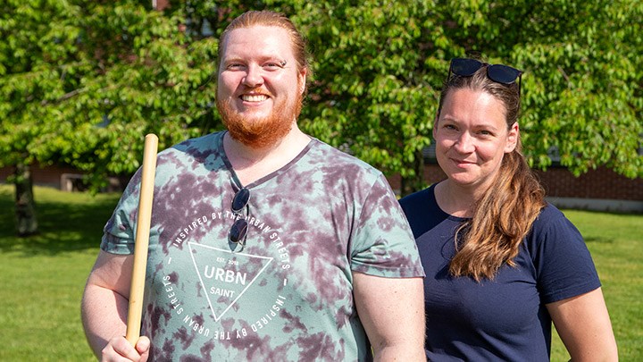 Oscar Kjell och Linea Braf står framför ett grönsaknde träd. Oscar håller i en kratta.