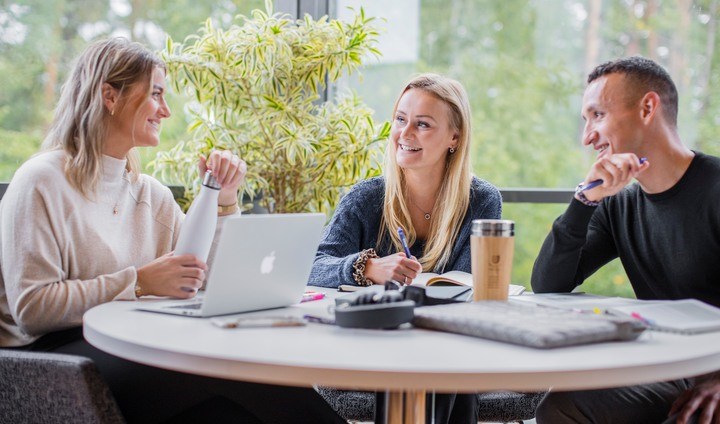 Två kvinnor och en man sitter runt ett bord och diskuterar