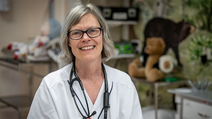 A woman wearing a white lab coat and a stethoscope around her neck.