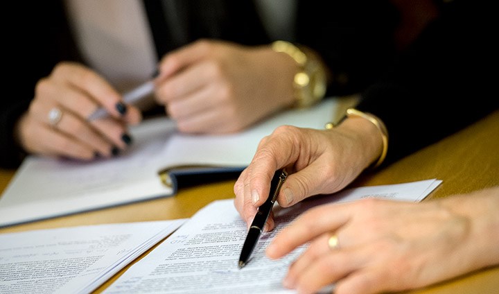 Two pair of hands with papers and pens.