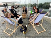 A few people sit in a ring on folding chairs.