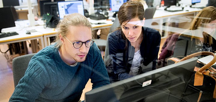 A man and woman in front of a computer screen.