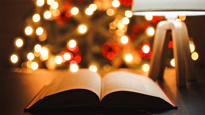 Photo of a table with a lamp and an open book.