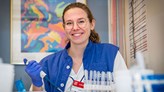 Isabella Visuri wearing a blue lab coat and holding a pipette.