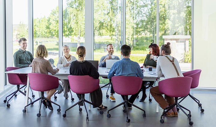 Människor runt ett konferensbord framför ett stort fönster.