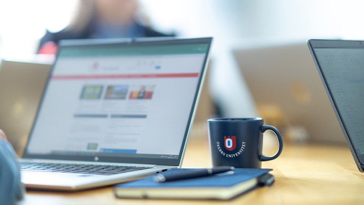 Photo of a computer and a mug on a table.