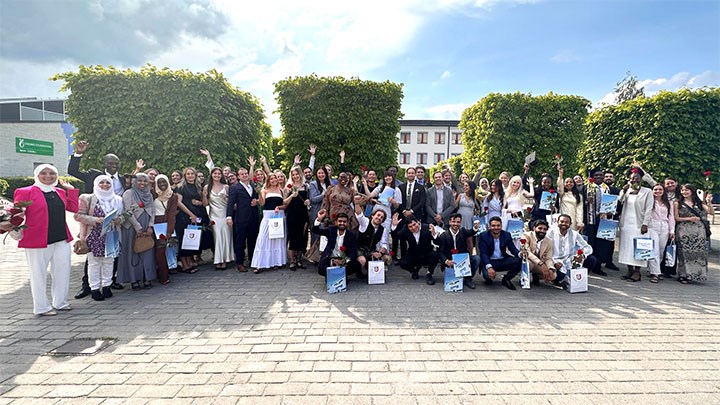 Ett stort gäng glada internationella mastersstudenter som tar examen.