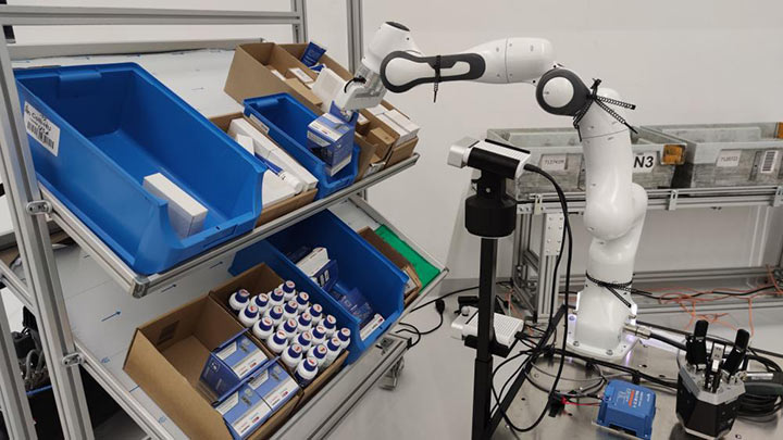 A robotic arm picks things in boxes.