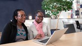 Two women sitting in front of a laptop.