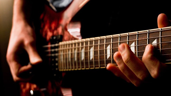 Närbild på elgitarr med händer