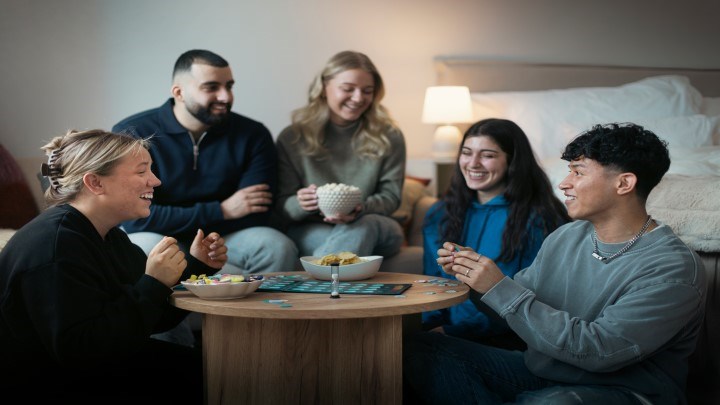 Glada studenter sitter och fikar samt spelar spel och skrattar.