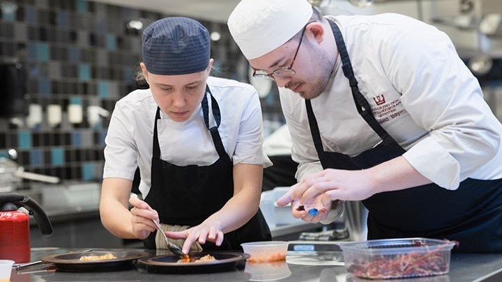 Två kockar förbereder mat i ett restaurangkök.